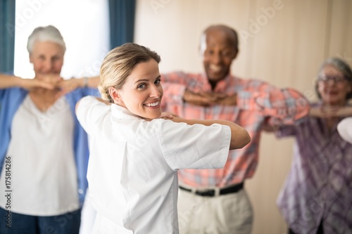 Rear view of smiling female doctor exercising with senior people
