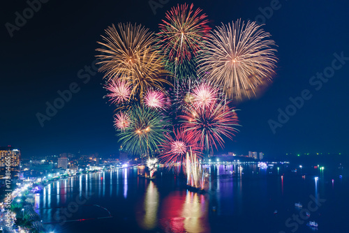 Colourful Fireworks over the sea beach with blue twilight sky background and city view