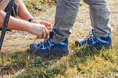 Close-up view of father tying shoelace for son during hiking in forest