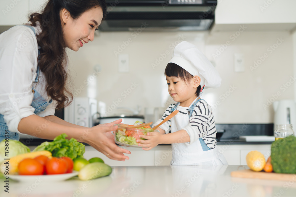 Child helping mother cooking in modern kitchen Child helping mother cooking in modern kitchen