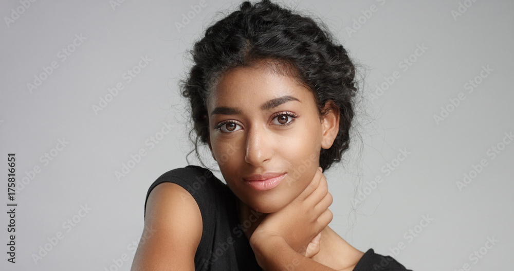 Attractive young Middle Eastern model touching her pretty face with flawless skin and smiling Attractive young Middle Eastern model touching her pretty face with flawless skin and smiling