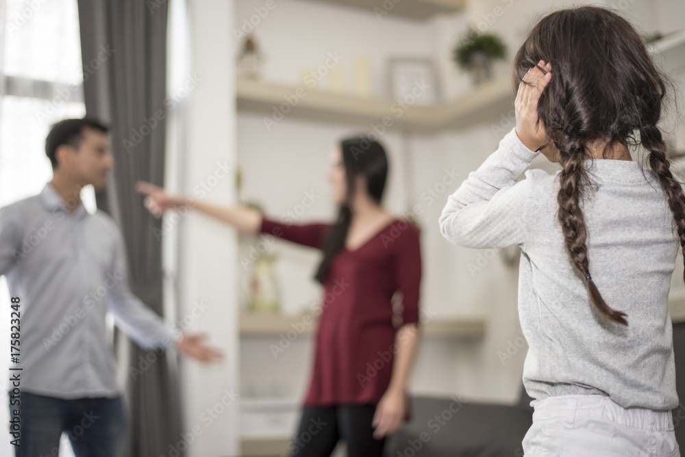 The girl puts her hands on her ear because she does not want to hear her parents quarrel. The girl puts her hands on her ear because she does not want to hear her parents quarrel.