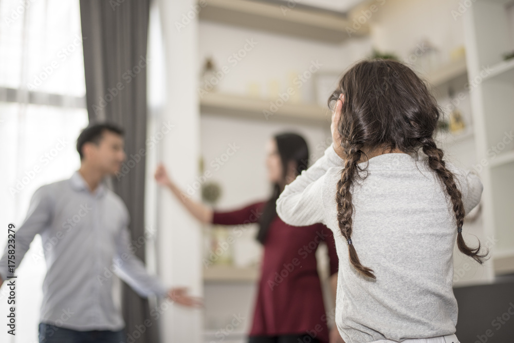The girl puts her hands on her ear because she does not want to hear her parents quarrel. The girl puts her hands on her ear because she does not want to hear her parents quarrel.