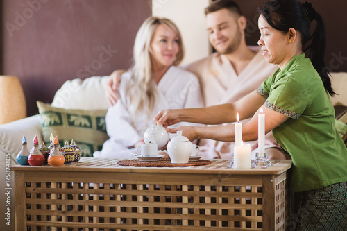 thai woman pouring tea for couple in spa room photo