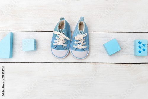 Baby boy shoes and wooden toys on wooden background. Flat lay