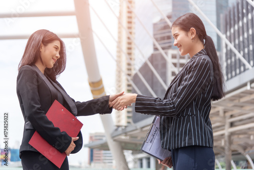 Two business women hand shake at outdoors with city and building background, Business and contact agreement concept