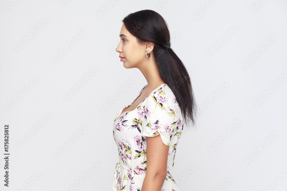 Side view of beautiful young adult woman, standing alone at gray background. Side view of beautiful young adult woman, standing alone at gray background.