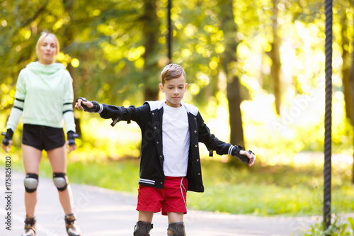 Happy young family roller skating in park photo