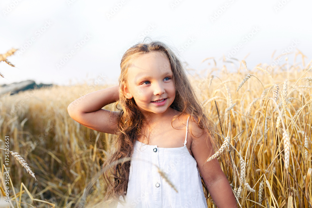 Little beautiful smiling girl on a gold wheat field walking at sunset. Happy five years old girl smiling and laughing in summer day at nature Little beautiful smiling girl on a gold wheat field walking at sunset. Happy five years old girl smiling and laughing in summer day at nature