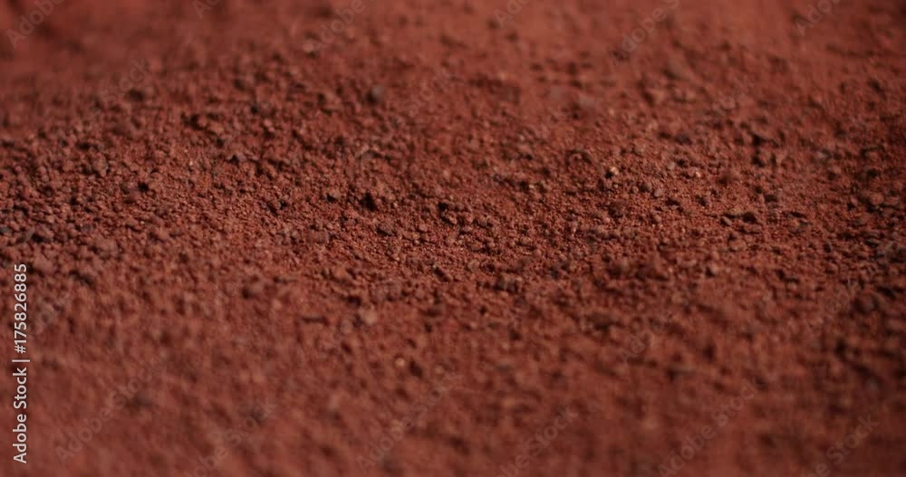 Close up shot of cocoa powder being sifted through a small handheld sift isolated on light blue Close up shot of cocoa powder being sifted through a small handheld sift isolated on light blue
