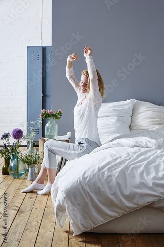 young attractive red haired woman enjoys getting up in the morning bedroom in studio scenery