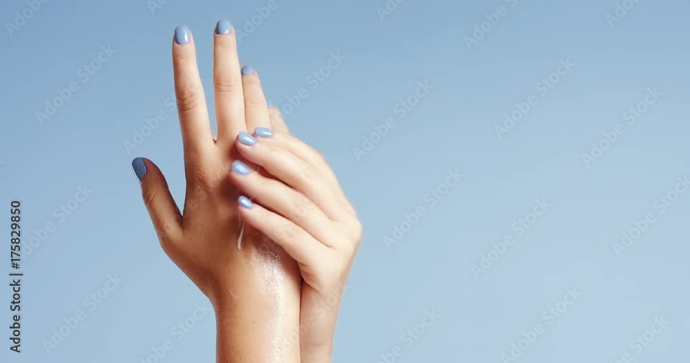 Clean well manicured hands of a young woman, applying hand cream, skin care on light blue background Clean well manicured hands of a young woman, applying hand cream, skin care on light blue background