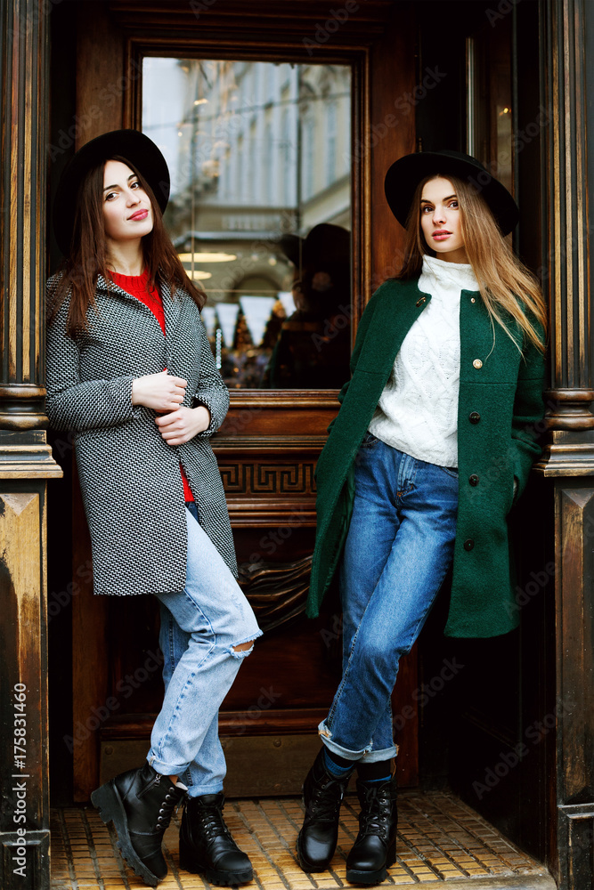 Outdoor full body portrait of two young beautiful fashionable girls