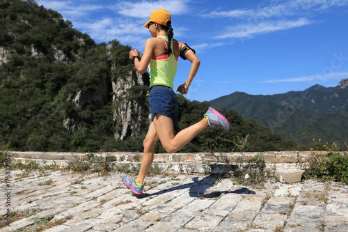 young fitness woman trail runner warming up on top of mountain