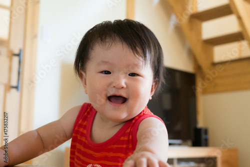 A baby standing up in the red tank top