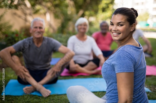 Smiling trainer sitting with senior people while exercising