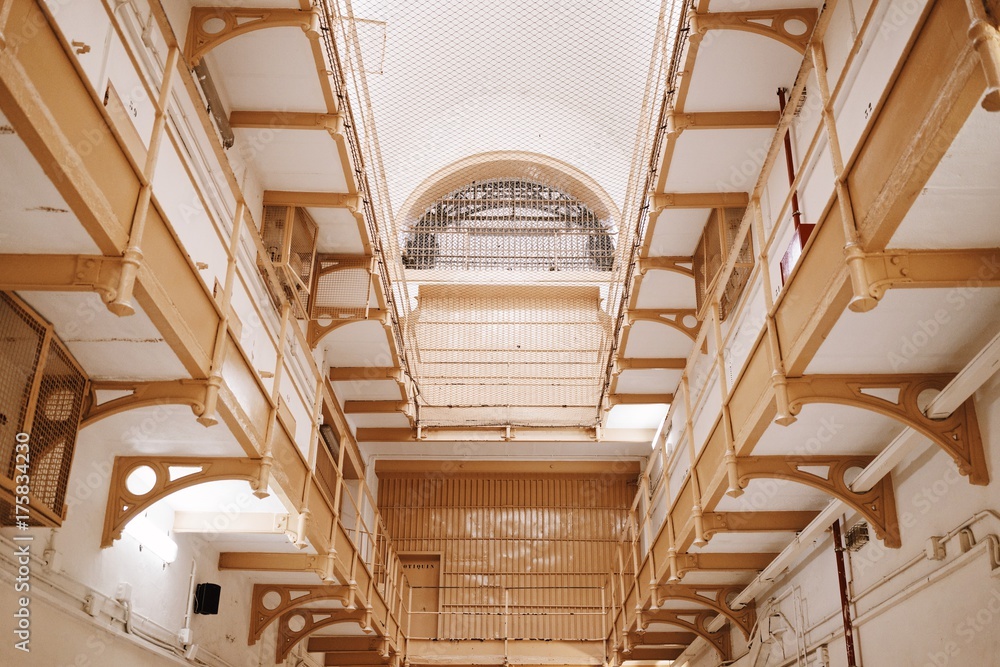 Obraz premium Empty corridor levels with cell rooms, white led lamps above closed doors inside of old prison.