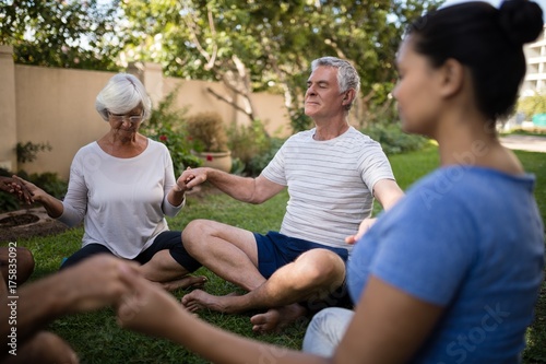 Senior people holding hands and meditating with trainer © WavebreakMediaMicro