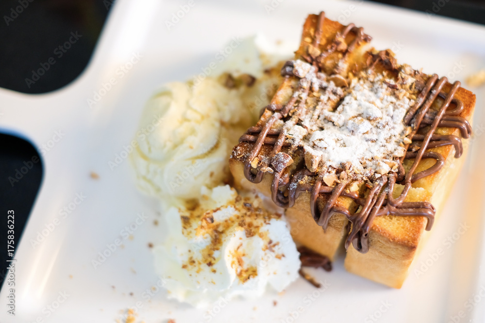The toast bread topped with chocolate & almonds, whipped cream and vanilla ice cream serve on white dish for dessert background or texture. The toast bread topped with chocolate & almonds, whipped cream and vanilla ice cream serve on white dish for dessert background or texture.