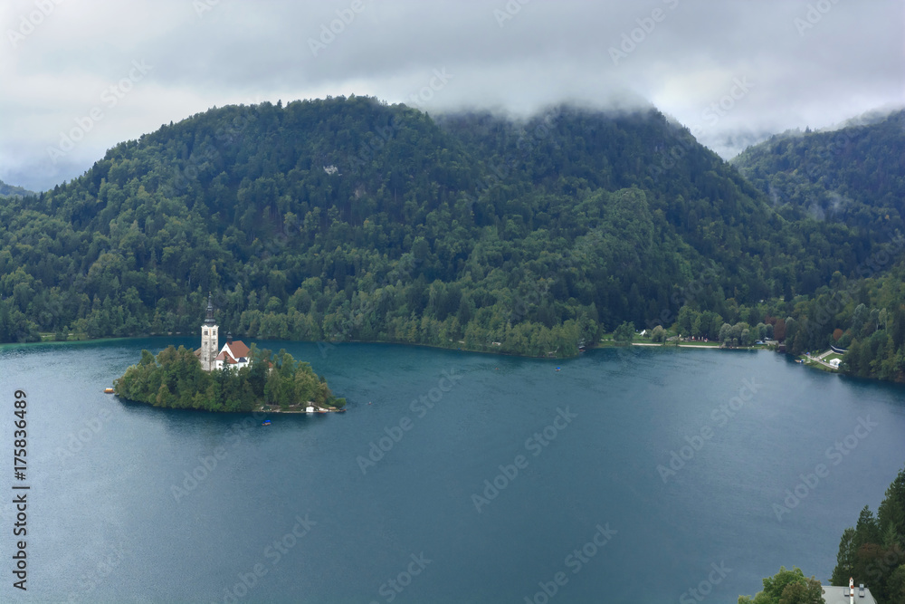 Bled with lake, island, castle and mountains in background in misty and rainy day Bled with lake, island, castle and mountains in background in misty and rainy day