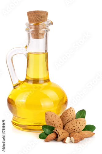 Bottle of almond oil and almonds with leaves isolated on white background