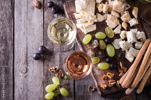 Different kinds of cheeses, wine, fruits and snacks on rustic wooden table . still life concept