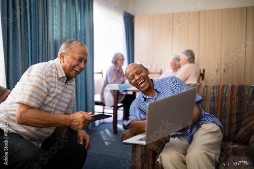 Happy senior friends looking at laptop