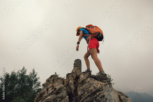 successful woman climber climbing rock on the top of mountain