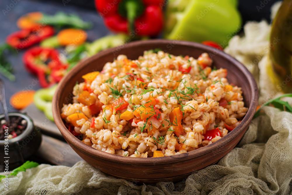 Vegetarian crumbly pearl barley porridge with vegetables in a dark background Vegetarian crumbly pearl barley porridge with vegetables in a dark background