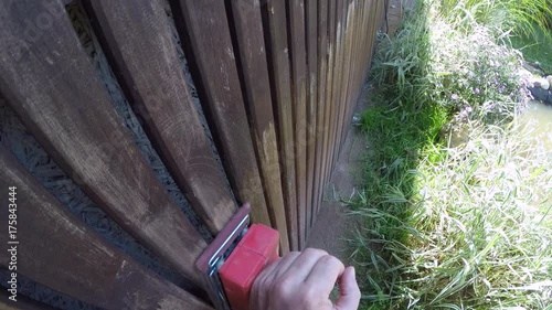 Point of view shot of a woman working on wooden fence near garden pond