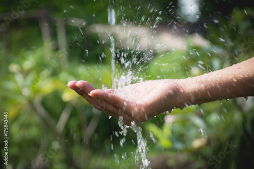 Water pouring in woman hand on nature background.