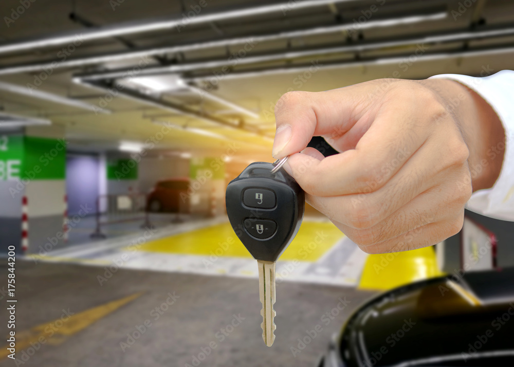 Man receiving car keys by a dealer against in cars parked at building with sunshine background.