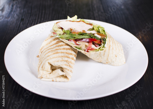 Burrito with grilled chicken and vegetables. Shawarma from juicy beef, lettuce, tomatoes, cucumbers, paprika and onion in pita bread.