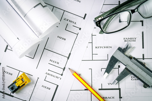 Top view of architect drawing on non identified architectural project with various of tools such as divider pencil eye glassed and small heavy equipment machine toys , toned color or instagram tone.