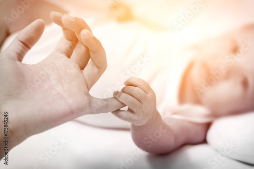 Soft tone of image of Close up a newborn baby s hand clutching his mother fingers.