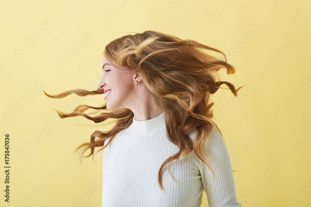 People, happiness, joy and positiveness concept. Studio shot of carefree  positive young woman smiling happily, turning head round, her wavy hair  flying away. Pretty female playing with her curly hair Stock Photo |