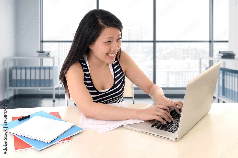 asian american student working with a smile at modern library office and studying for exam with computer laptop asian american student working with a smile at modern library office and studying for exam with computer laptop