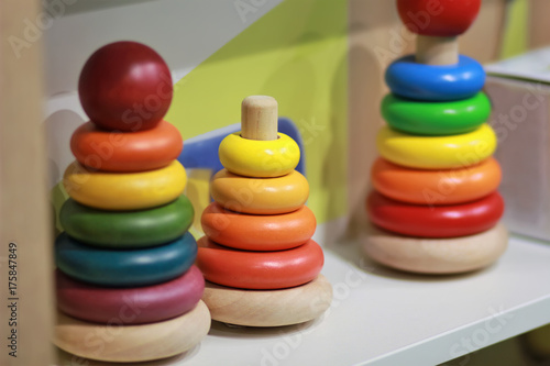Bright colorful wooden children toy pyramids on a shelf in the shop. Toy shopping
