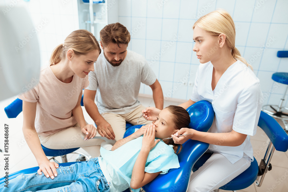 Obraz premium A man and a woman led the girl to see a dentist. The girl is afraid
