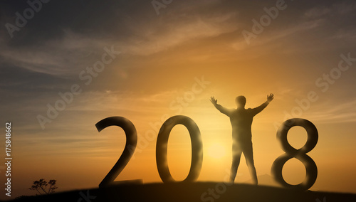 Silhouette man stand on the top of mountain and look through the sunrise, sunset and give two hand up to feel like a winner, success, finish,reach a goal of live, jobs,work with in 2018 new years