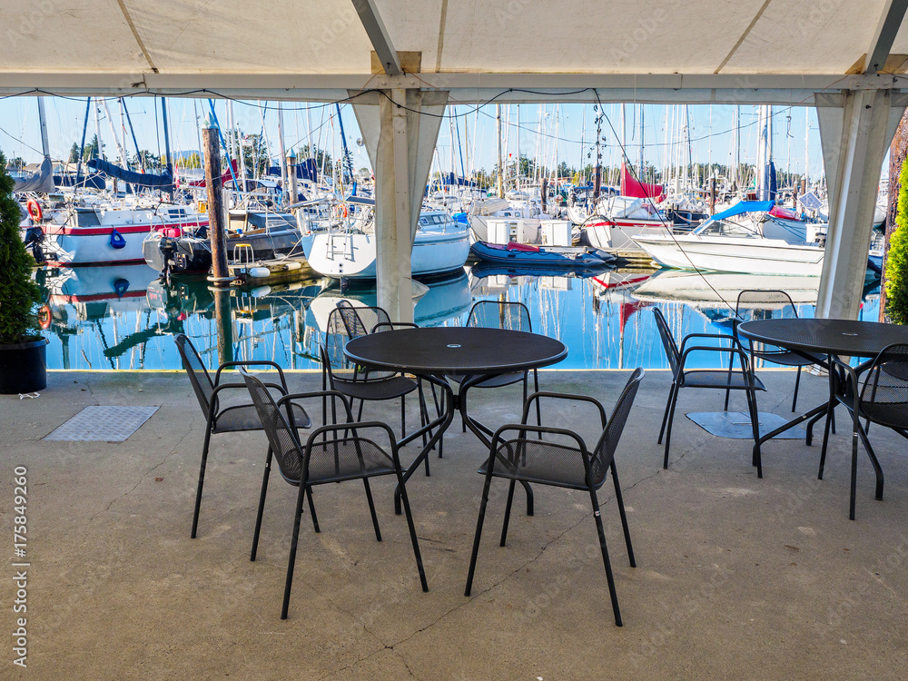 Table and chairs under the tent overlooking marina with yachts and sailboats