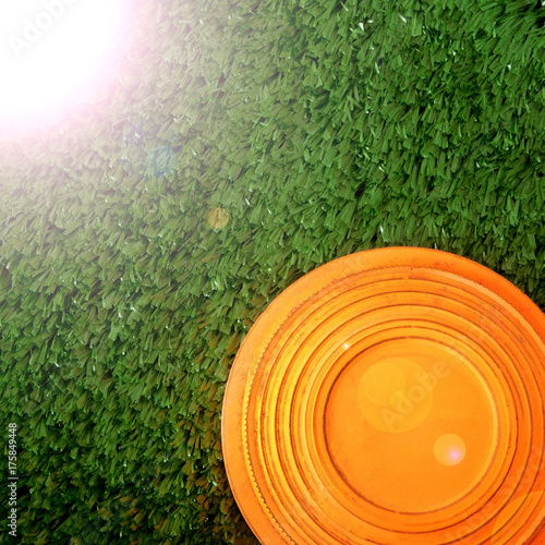 Flying target plate for shotgun sport is lying on the green grass. Copy space. Sun ray imitation photo