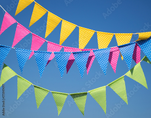 Fototapeta Naklejka Na Ścianę i Meble -  garlands with multi-colored flags against a background of blue sky. garland of pink, green, blue and yellow flags. festive background. Party flags decoration on outdoor