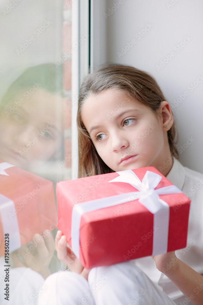 pretty little girl dreaming by the window holding gift pretty little girl dreaming by the window holding gift