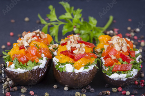 Baked eggplants stuffed with vegetable, walnut and cream cheese on a black slate background, close up