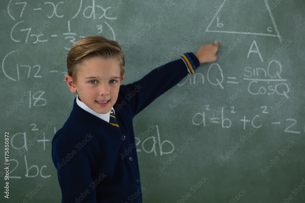 Schoolboy solving maths formula on chalkboard Schoolboy solving maths formula on chalkboard