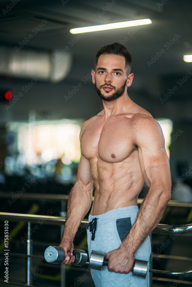 A young athlete trains in the gym. Shows the muscles of the back and chest A young athlete trains in the gym. Shows the muscles of the back and chest