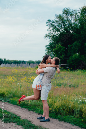 young loving couple in the park outdoors against the trees