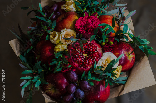 fresh autumn vegetarian fruity bouquet of apples, grapes, pomegranates and roses, with green leaves on a dark background