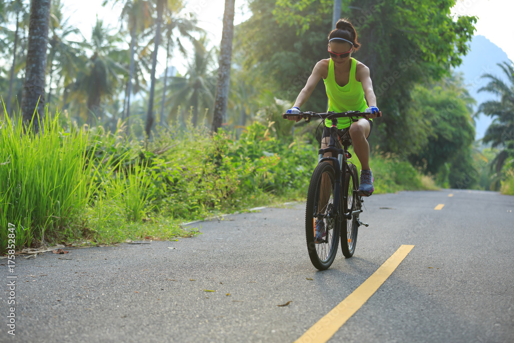 Young  woman cycling on tropical forest trail